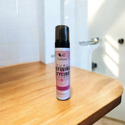 Curlura Curl Defining Styling Mousse for curly hair on a wooden surface in a bathroom setting.